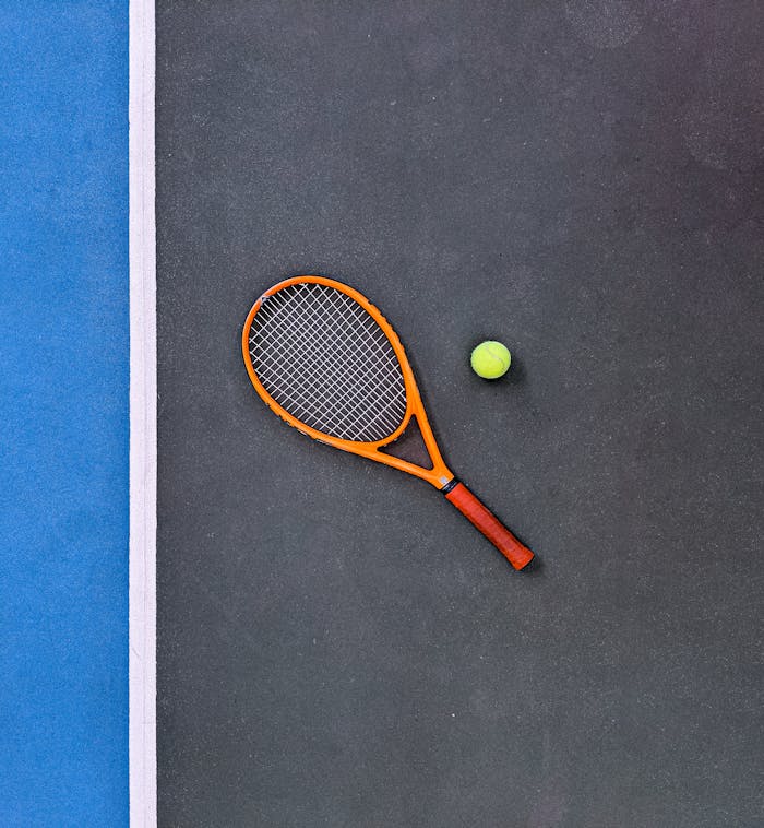 A tennis racket and ball on a court, emphasizing sports equipment essentials.